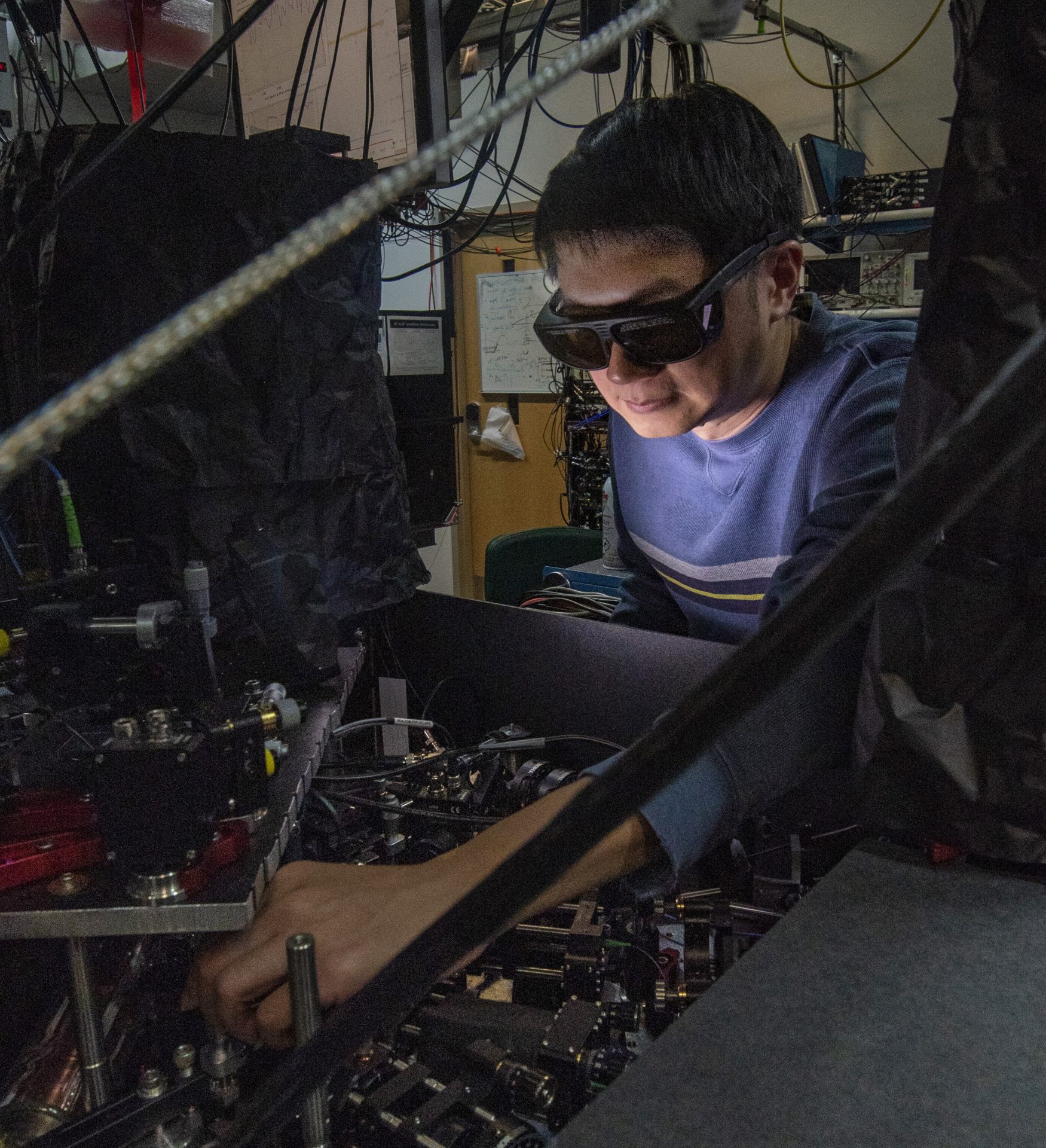 NIST physicist James Chin-wen Chou adjusts one of the laser beams used to manipulate an atom and a molecule in experiments that could help build hybrid quantum information systems. Credit: Burrus/NIST